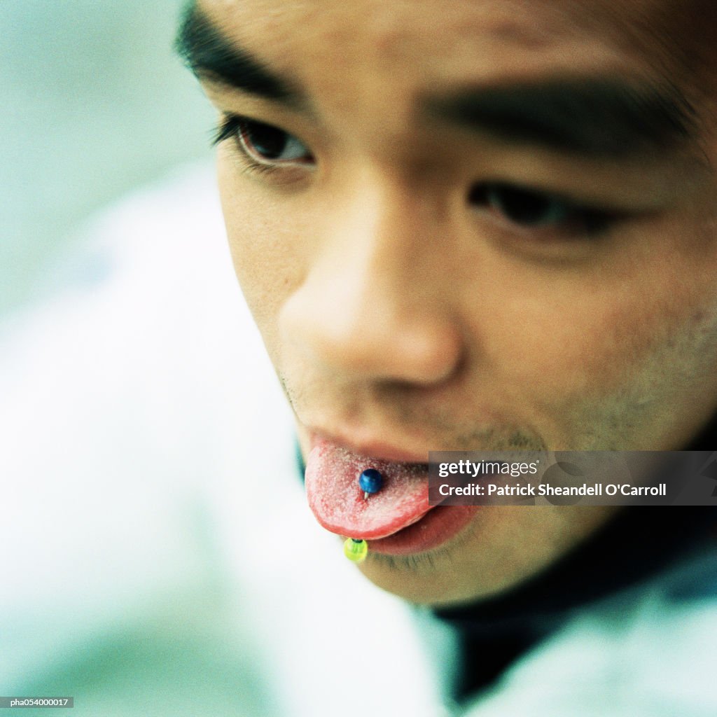 Male teenager with a tongue piercing, portrait