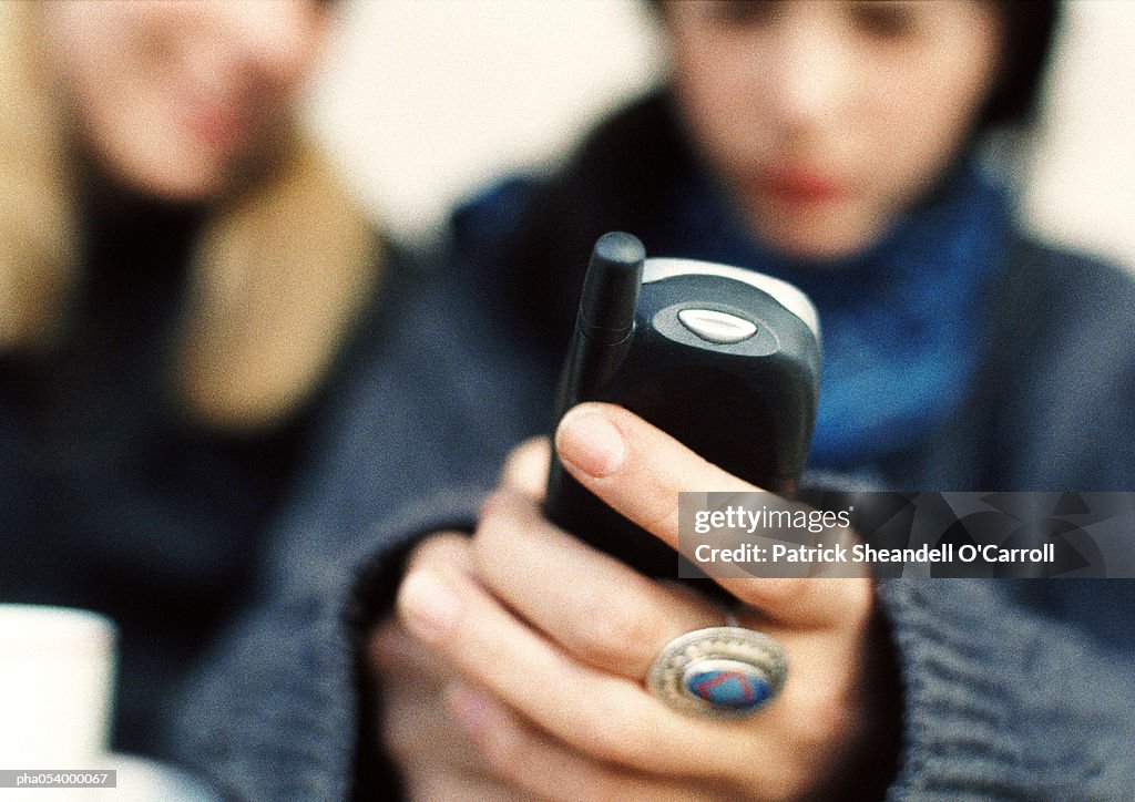 Hands holding a cell phone, blurred background