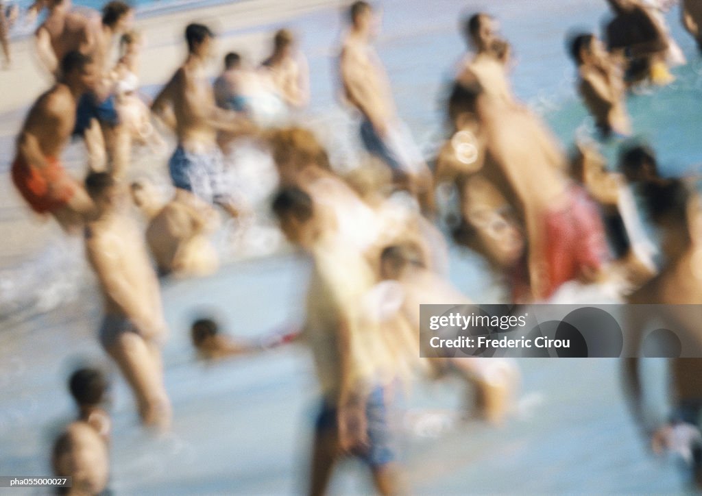 People standing in water at beach, blurred