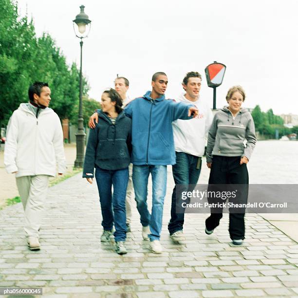 six young people walking together on cobblestones - pandilla grupo de personas fotografías e imágenes de stock