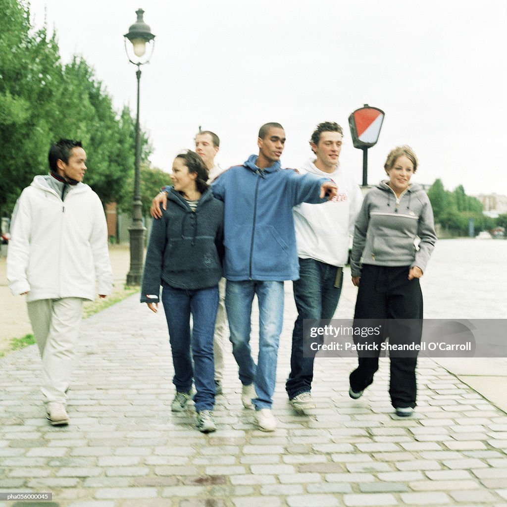 Six young people walking together on cobblestones