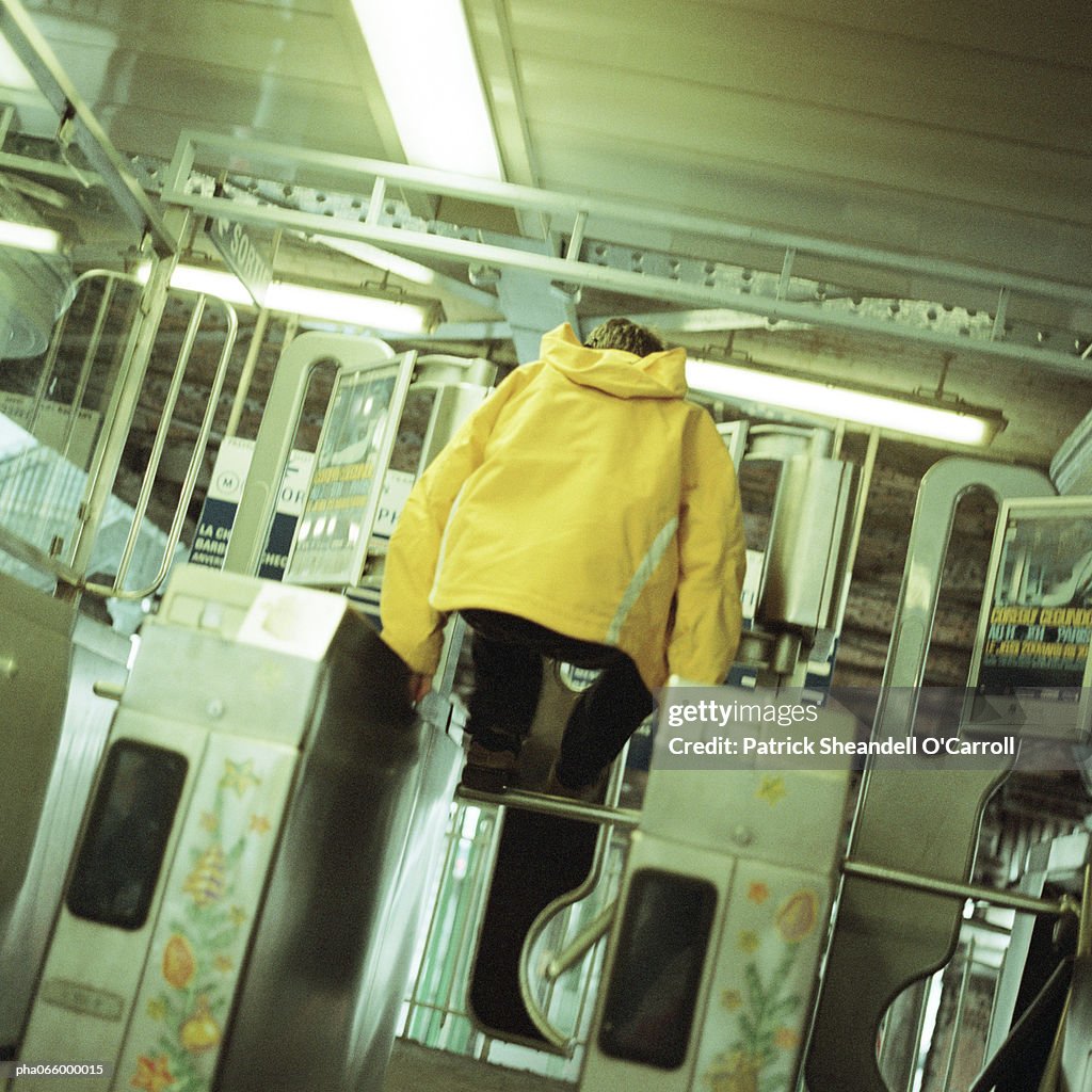 Young man jumping over turnstile in subway