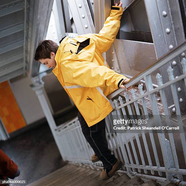 man in raincoat sliding down handrail - sliding door stockfoto's en -beelden