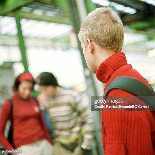 young man looking at young women, blurred in background, on subway platform, rear view - square neckline ストックフォトと画像
