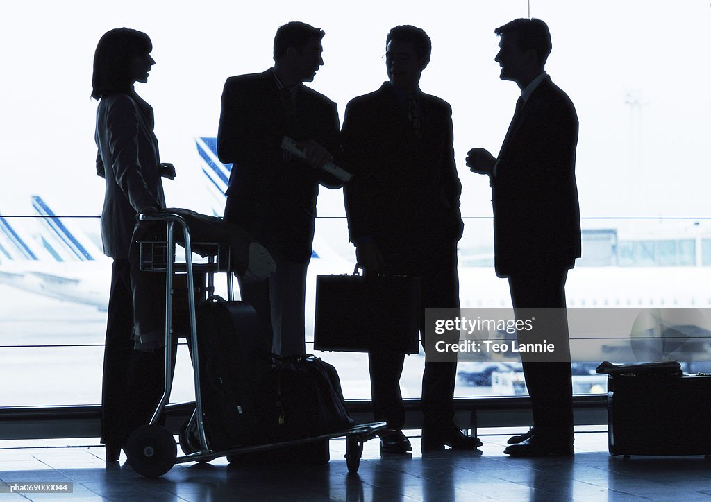 Group of business people standing inside airport, silhouette.