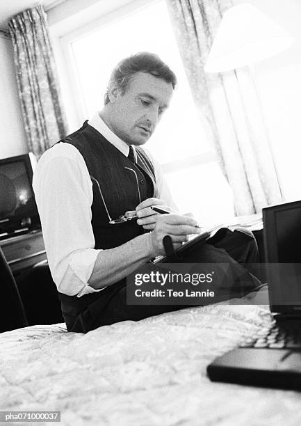businessman working while sitting on bed in hotel room, blurred, b&w. - b 47 - fotografias e filmes do acervo
