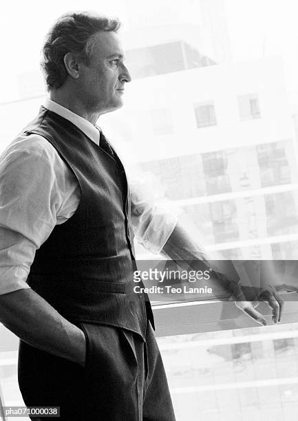 businessman standing next to window looking out, side view, b&w. - b 47 - fotografias e filmes do acervo