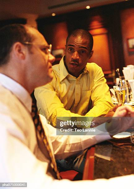 businessmen sitting at bar talking, side view. - africain stockfoto's en -beelden