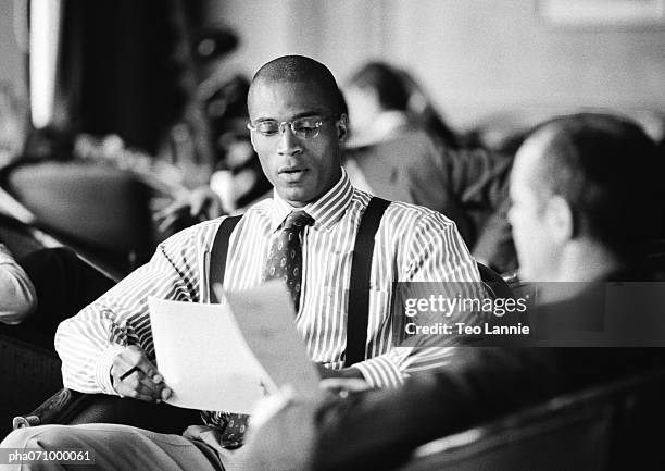 businessmen sitting together looking over papers, b&w. - africain stockfoto's en -beelden