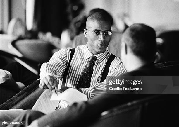 businessmen sitting discussing document, b&w. - africain stockfoto's en -beelden