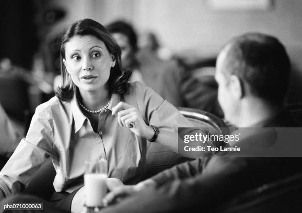 businessman and businesswoman sitting together talking, b&w. - fokus-auf-den-hintergrund stock-fotos und bilder