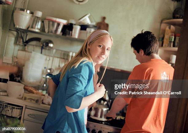 teenage girl looking over shoulder at camera, in kitchen, next to teenage boy, rear view, tilt. - boy cooking stock pictures, royalty-free photos & images