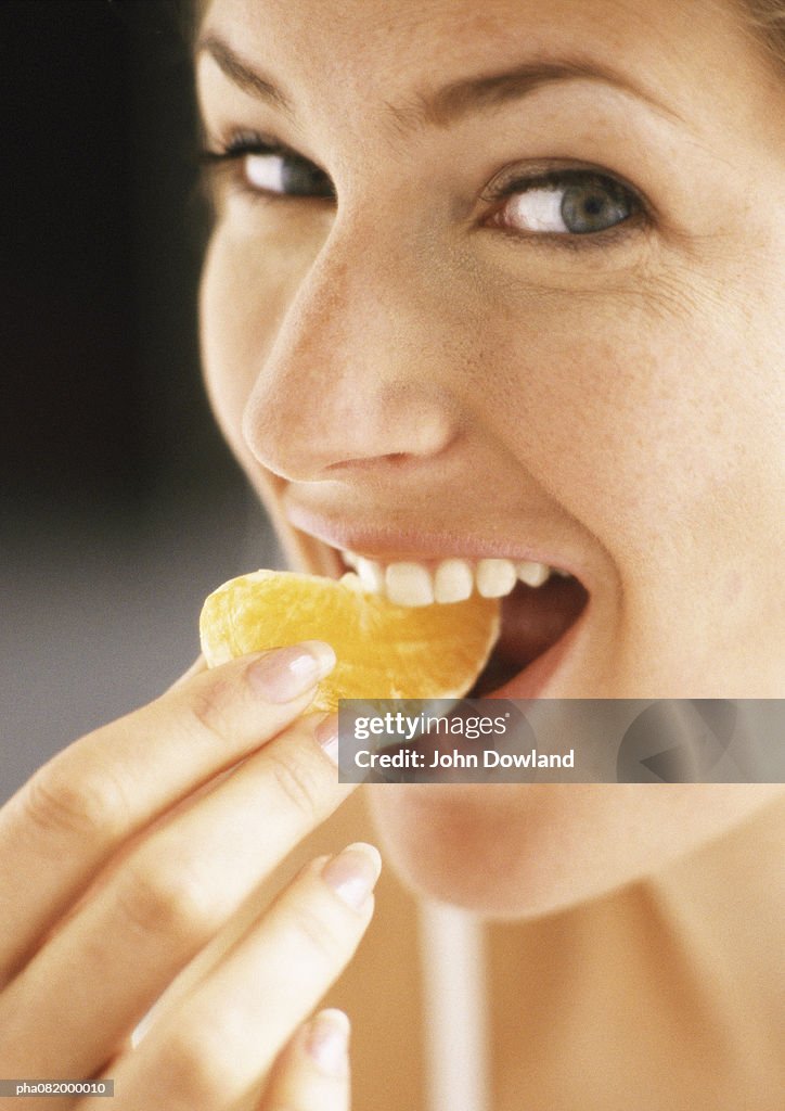 Woman eating orange slice, close-up