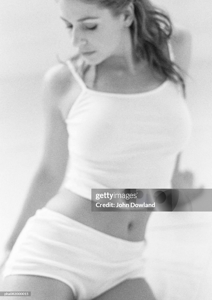 Woman jutting out hip, looking down, B&W.
