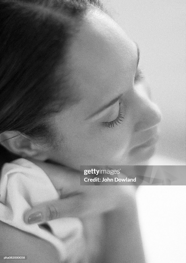 Woman resting head on hand, side view, close-up, B&W.