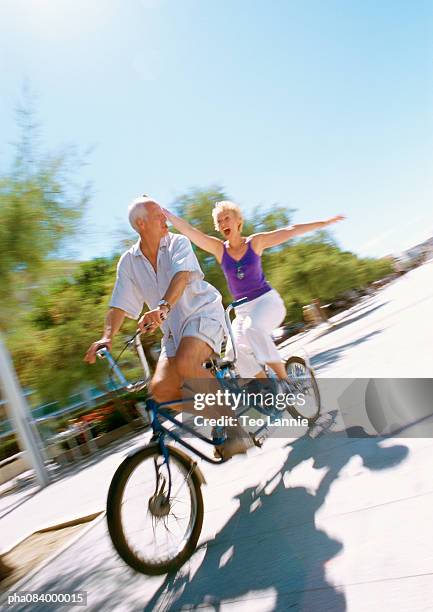 senior man and woman riding together on tandem bike, blurred. - tandem bicycle bildbanksfoton och bilder