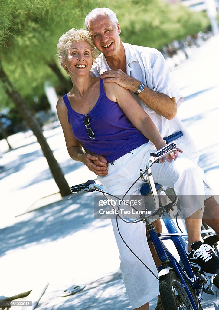 Senior man and woman on tandem bike, portrait.