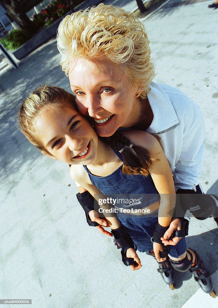 Senior woman and young girl on in line skates, smiling.