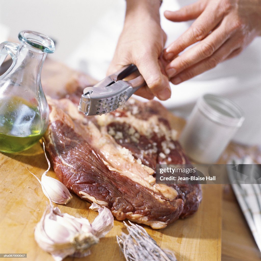 Close-up of meat being prepared with crushed garlic.