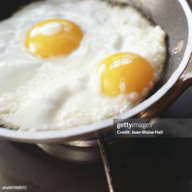 close-up of eggs being cooked in a pan. - pan stock-fotos und bilder