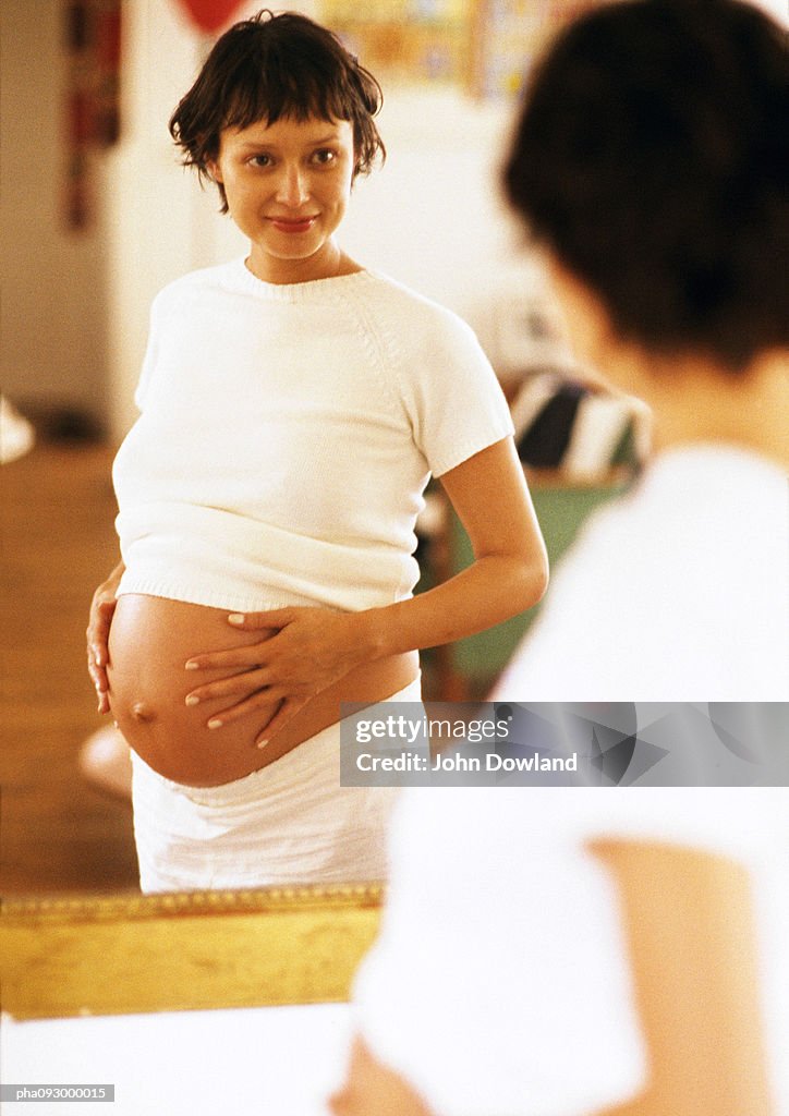 Pregnant woman looking at herself in mirror