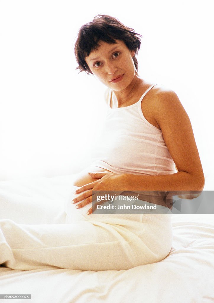 Pregnant woman with hands on stomach, portrait