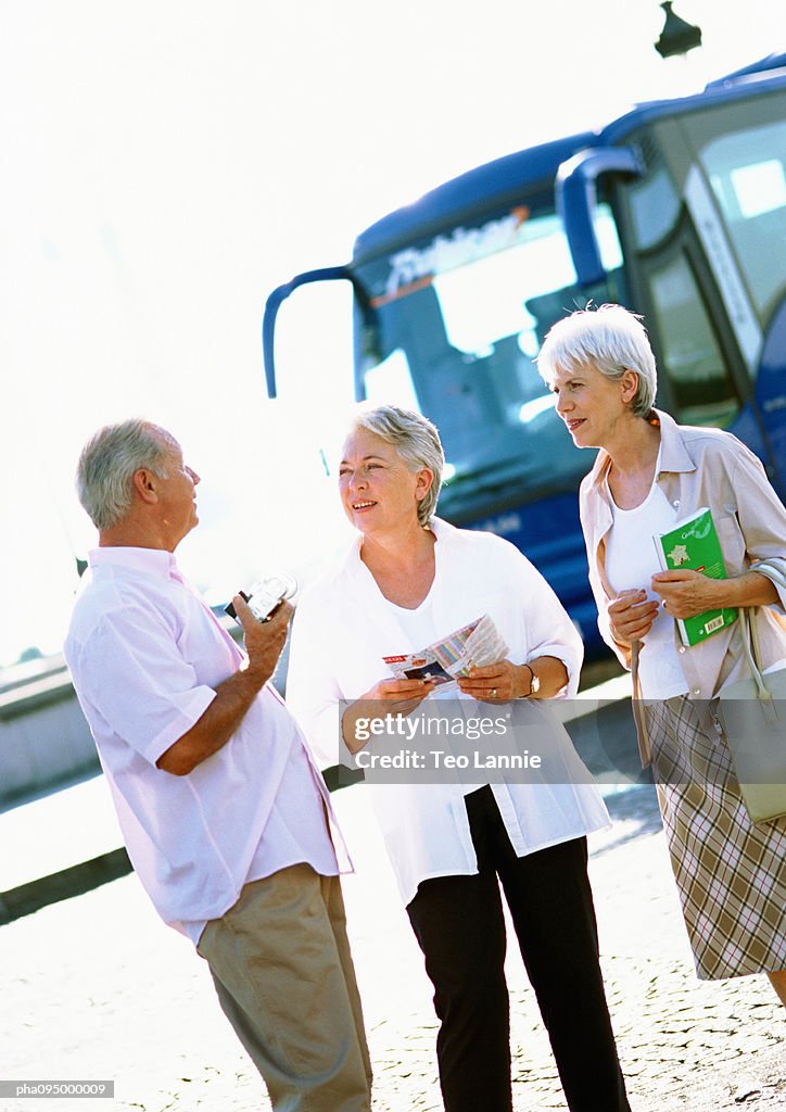 Mature women and man talking in front of a bus