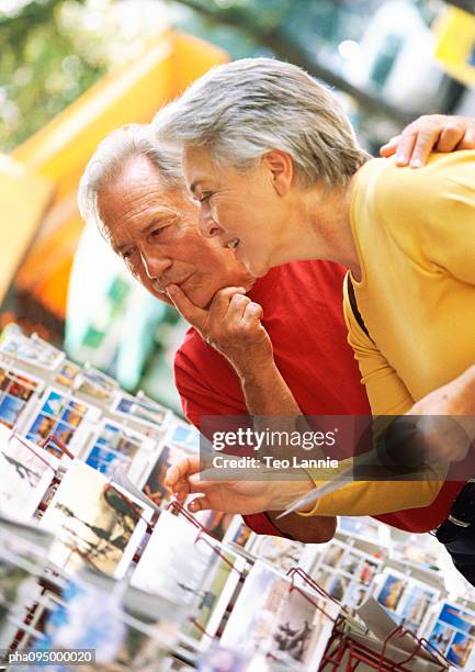 mature woman and man looking at postcards - travel11 stock pictures, royalty-free photos & images