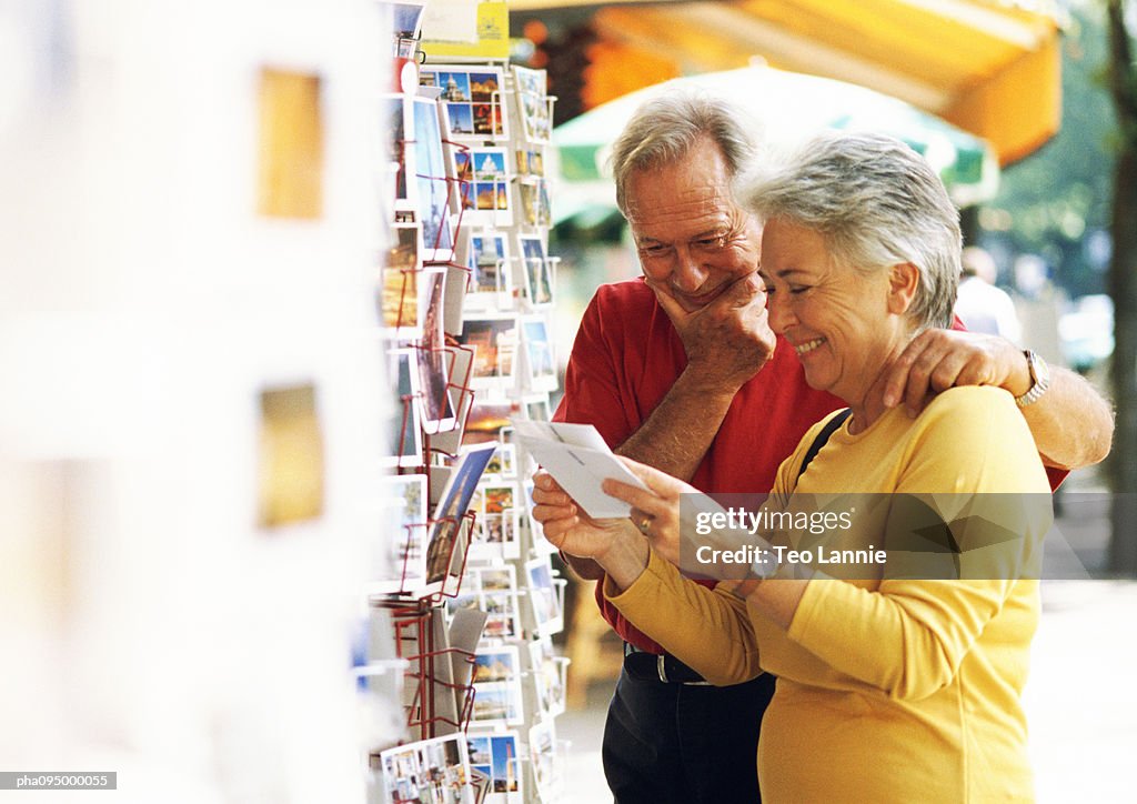 Mature man and woman looking at postcards in the street