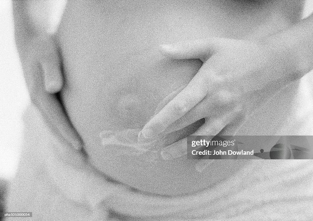 Pregnant woman applying cream to belly, b&w