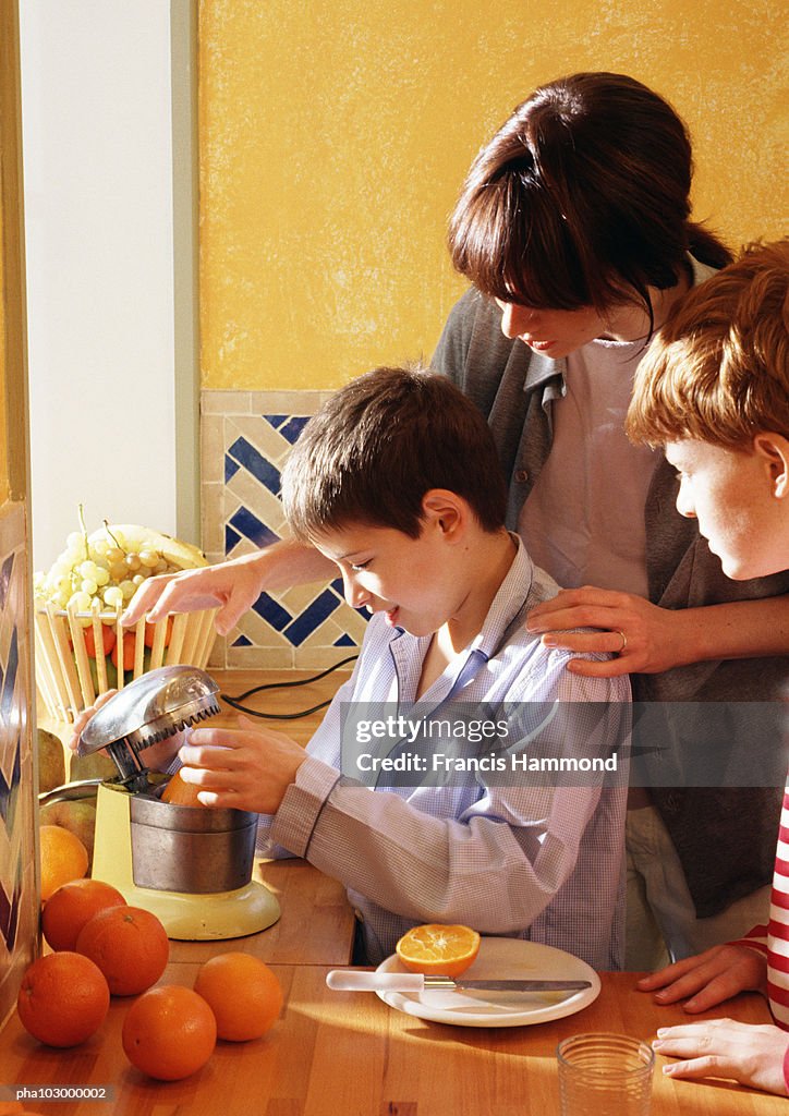 Woman and children squeezing oranges