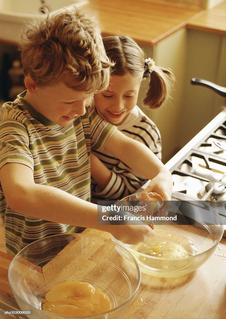 Two children smiling, one beating up egg whites