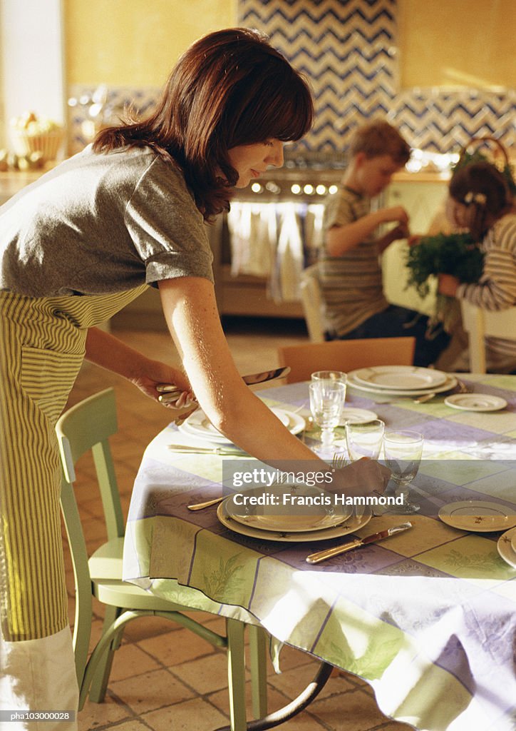 Woman setting the table, side view