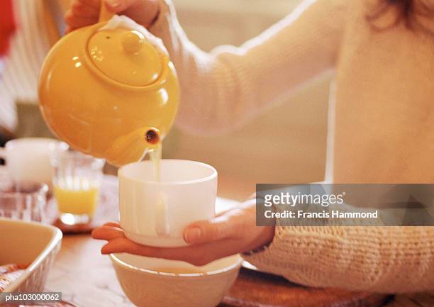 hands holding teapot above cup - pour spout stock pictures, royalty-free photos & images