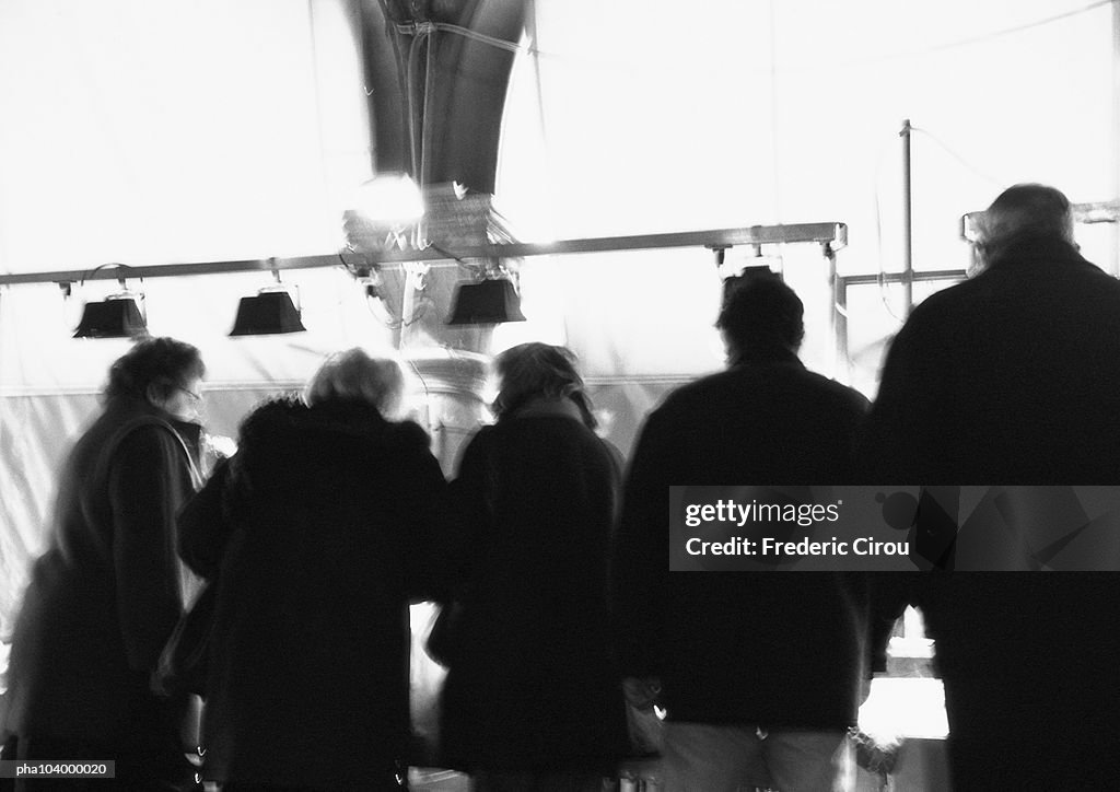 People standing side by side, rear view, b&w