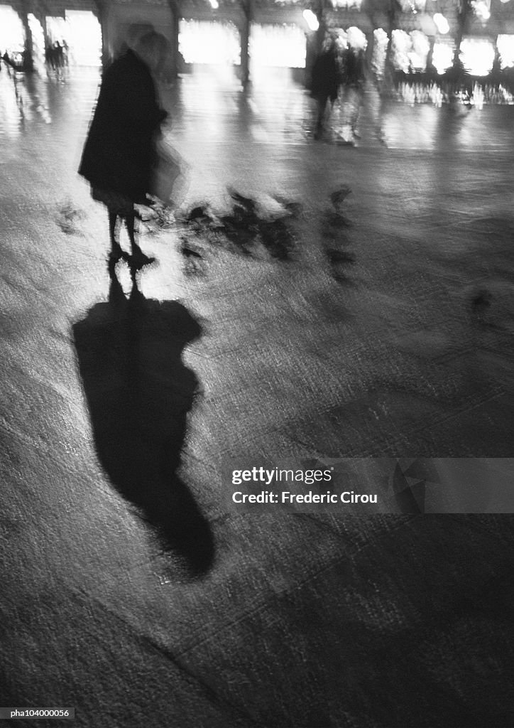 Person standing on wet pavement, blurred, b&w