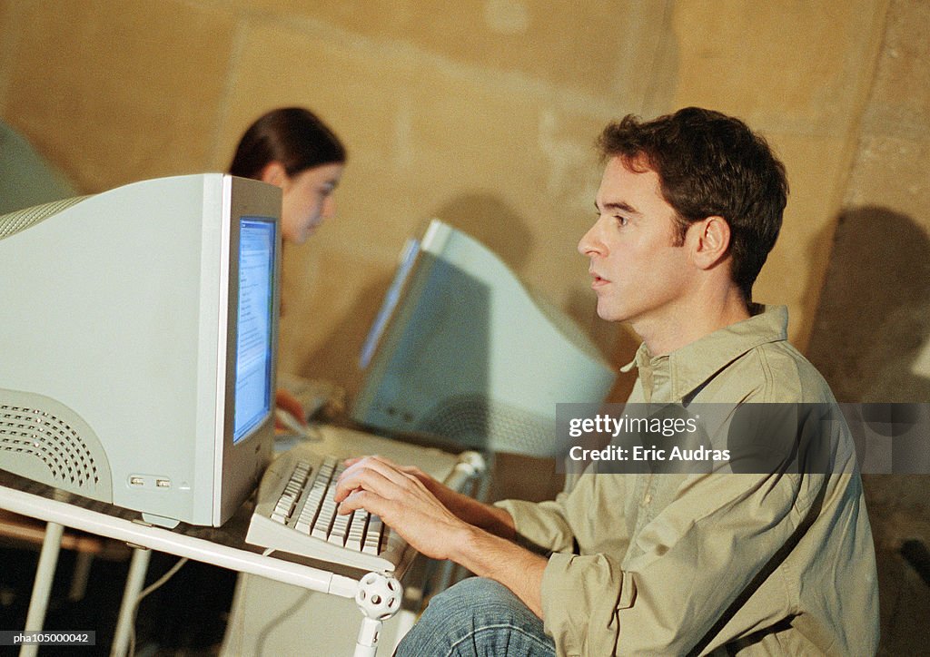 Man and woman working on computers in office
