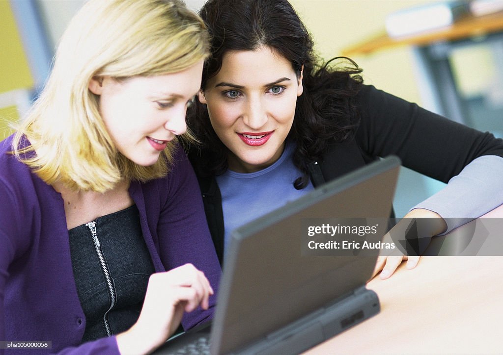Two women sitting in front of a laptop computer