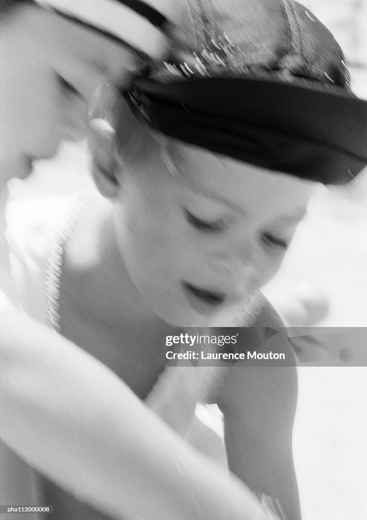 Two boys with hats looking down, close-up, b&w