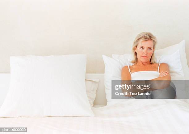 woman lying in bed, arms folded over chest - bachelor stock pictures, royalty-free photos & images
