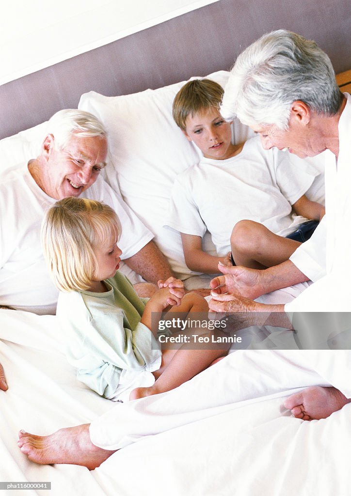 Grandparents and children sitting on bed