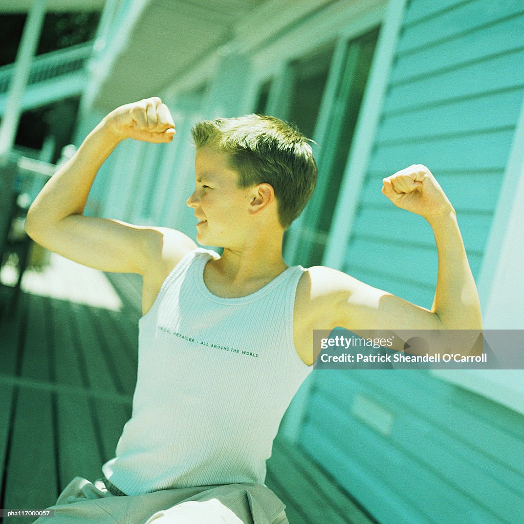 Teenage boy flexing arm muscles