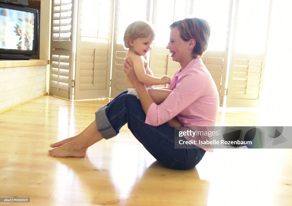 Woman sitting on floor, holding baby
