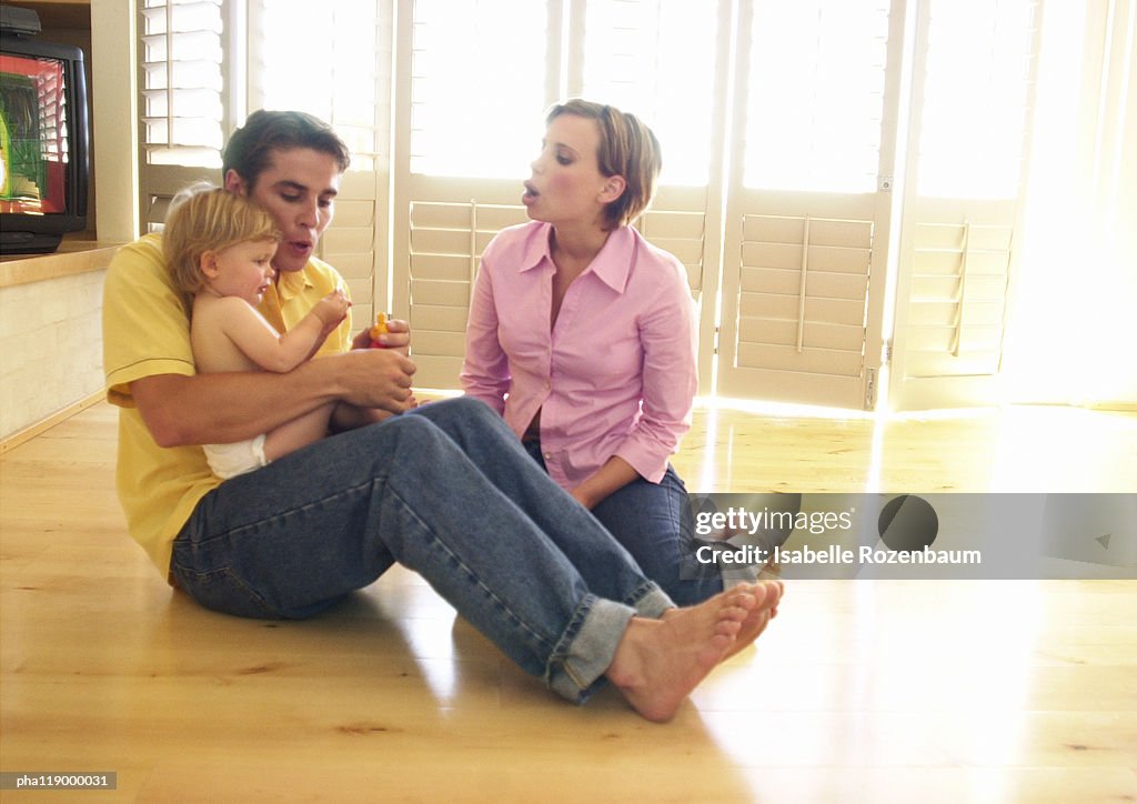 Couple sitting on floor, man hugging baby