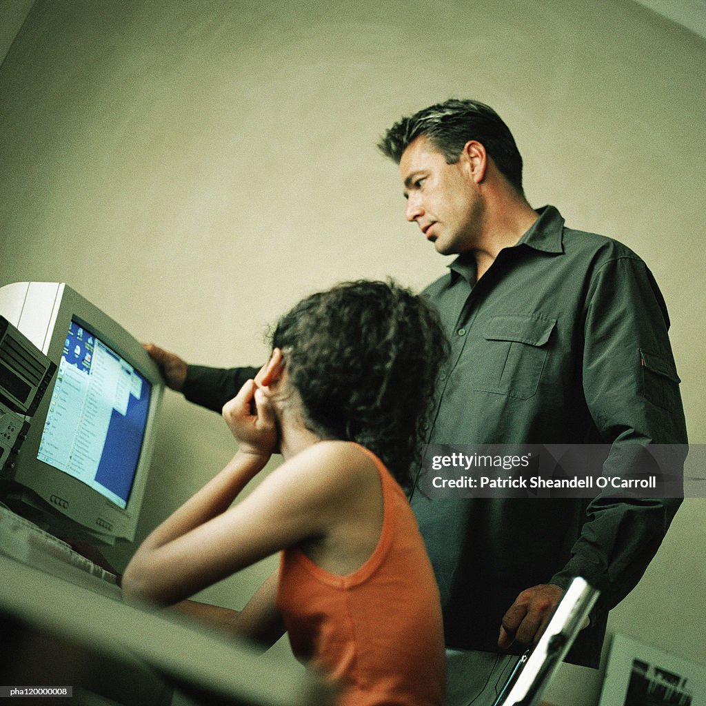 Mature man and teenage girl in front of computer