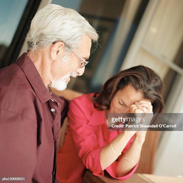 senior man looking at woman with hands on brow - daughter crying stock pictures, royalty-free photos & images