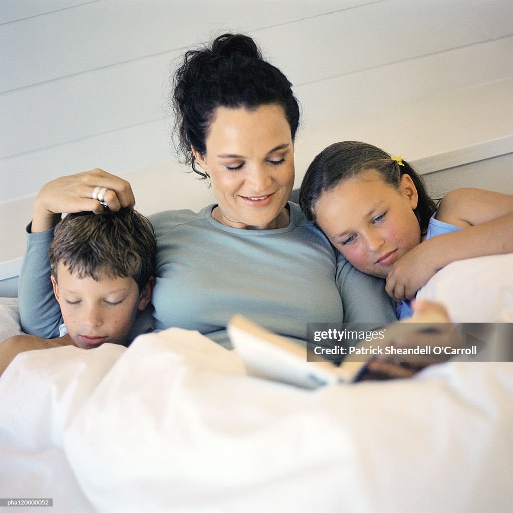 Mother laying in bed between children