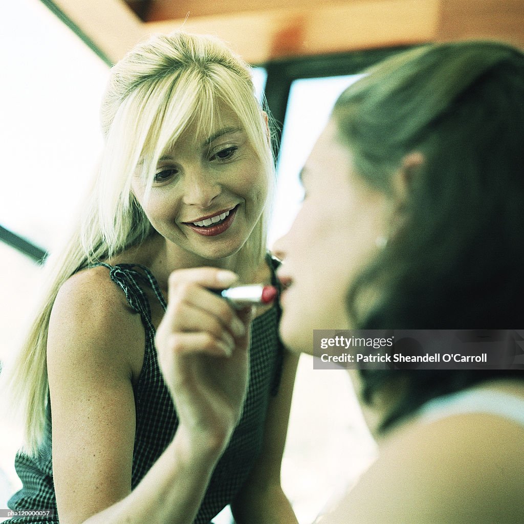 Woman applying make up on teenage girl, blurred