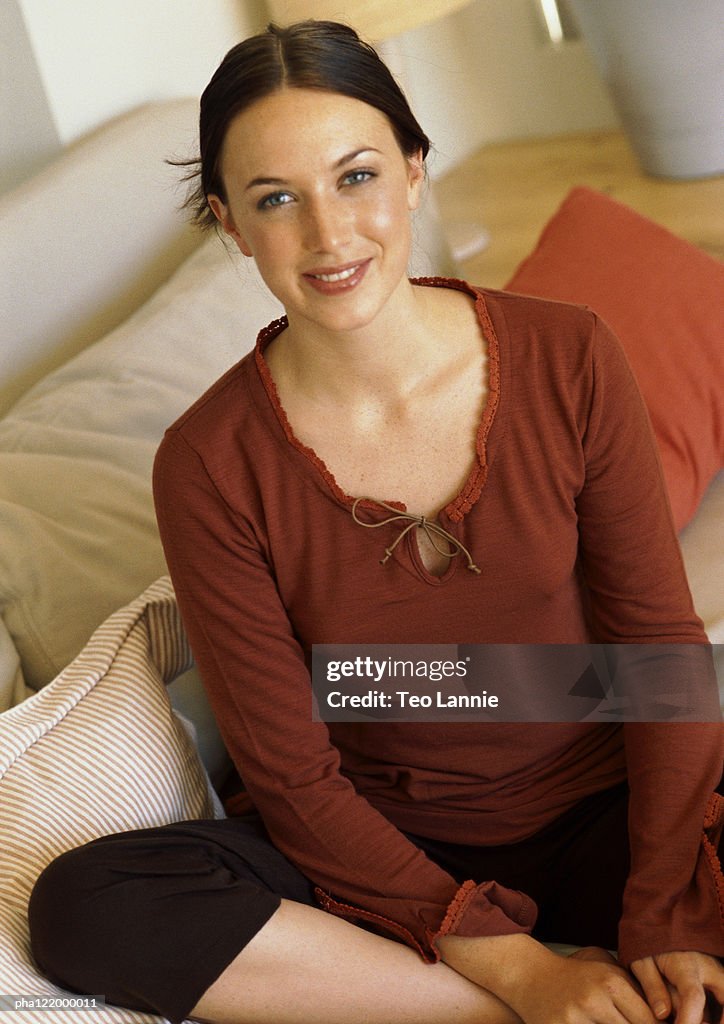 Woman sitting on sofa, smiling