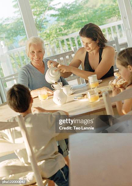 grandmother, mother and children having breakfast - pitorro fotografías e imágenes de stock